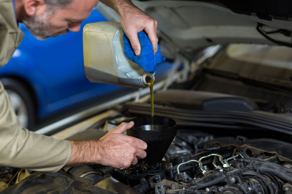 Mechanic Pouring Oil Into Car Engine